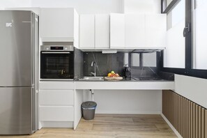 A modern kitchen with a stainless steel refrigerator, built-in oven, and a sink with a marble backsplash. - Travel Habitat Loft Sea & Port (Valencia)