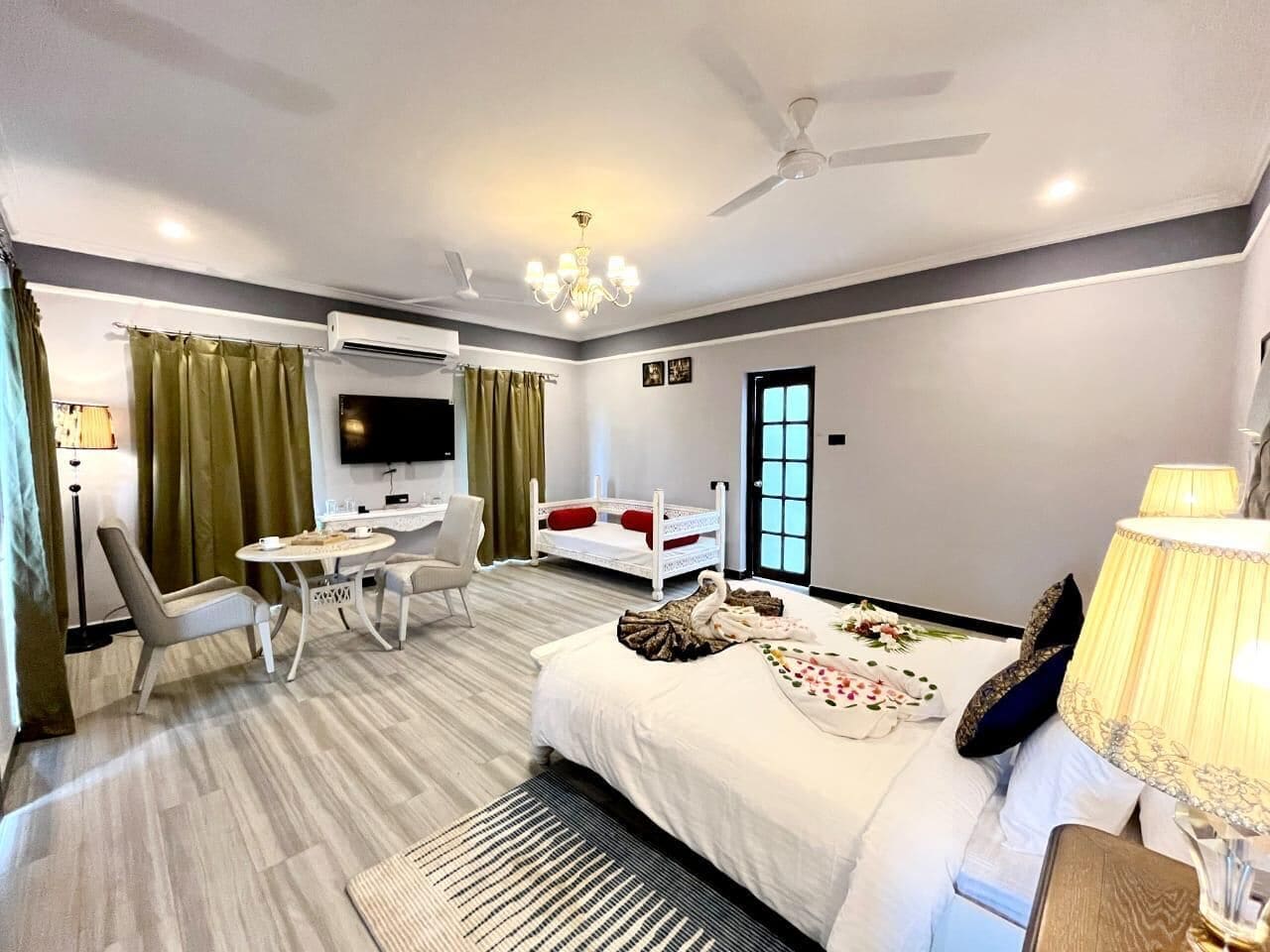A hotel room with a bed, a desk, a chair, a TV, and a ceiling fan.