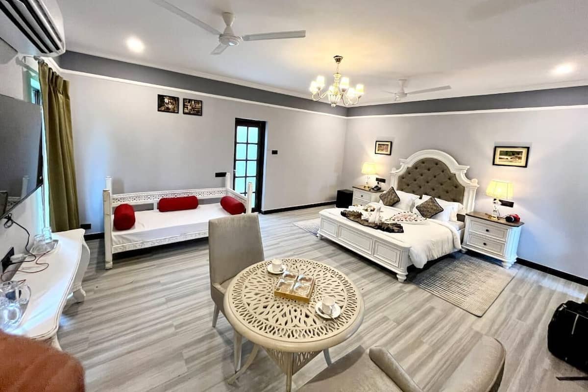 Una habitación de hotel con cama, mesita de noche, una silla, una mesa redonda y un ventilador de techo.