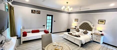A hotel room with a bed, a bedside table, a chair, a round table, and a ceiling fan.