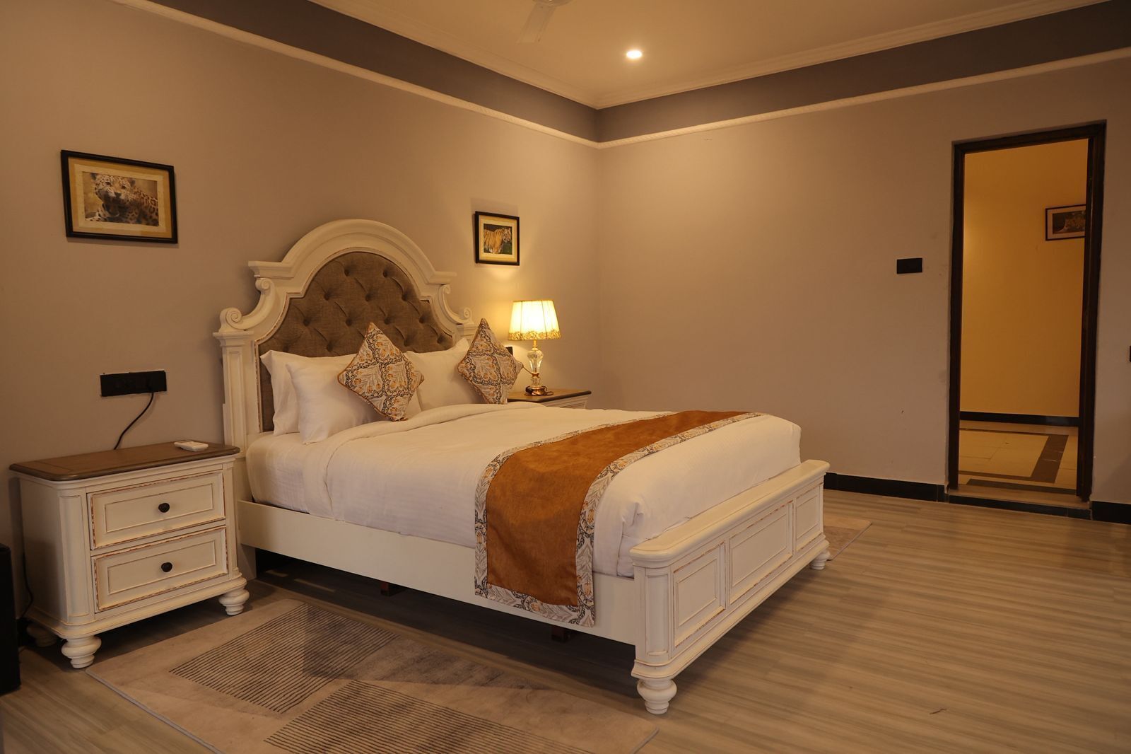 Un dormitorio con cama, mesita de noche, lámpara y espejo.