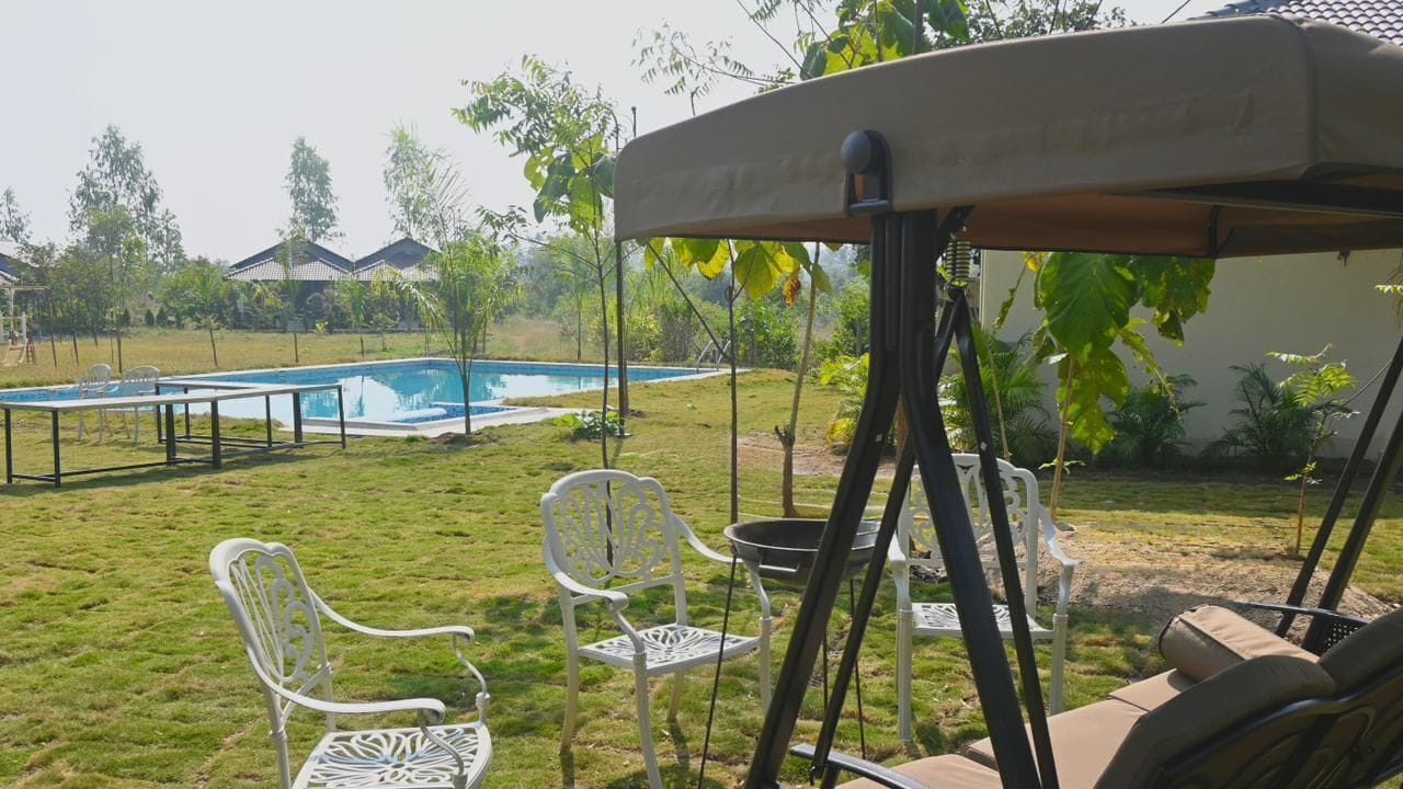 A backyard with a pool, outdoor furniture, and a swing set.