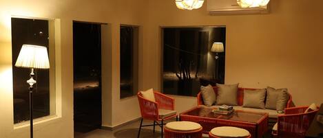 A cozy room with a sofa, chairs, a coffee table, and a lamp.