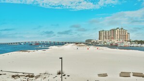 Une plage avec une jetée, un grand hôtel et un ciel dégagé.