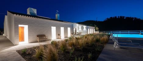 A modern building with a pool, outdoor seating, and a well-maintained garden.