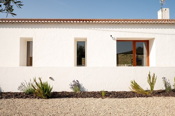 A white building with a tiled roof, two windows, and a door.