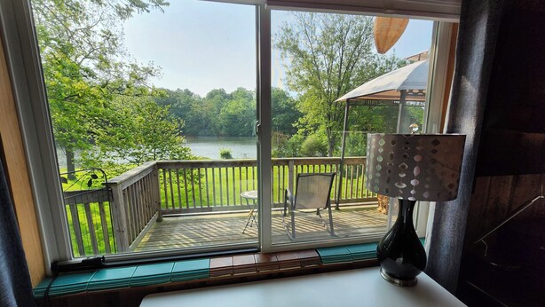 Een kamer met uitzicht op een meer, een tafel, een stoel en een lamp.