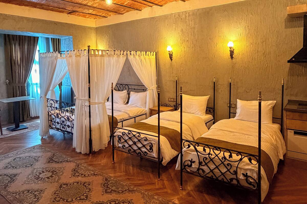 Un dormitorio con dos camas, una cama con dosel, techo de madera y alfombra estampada.