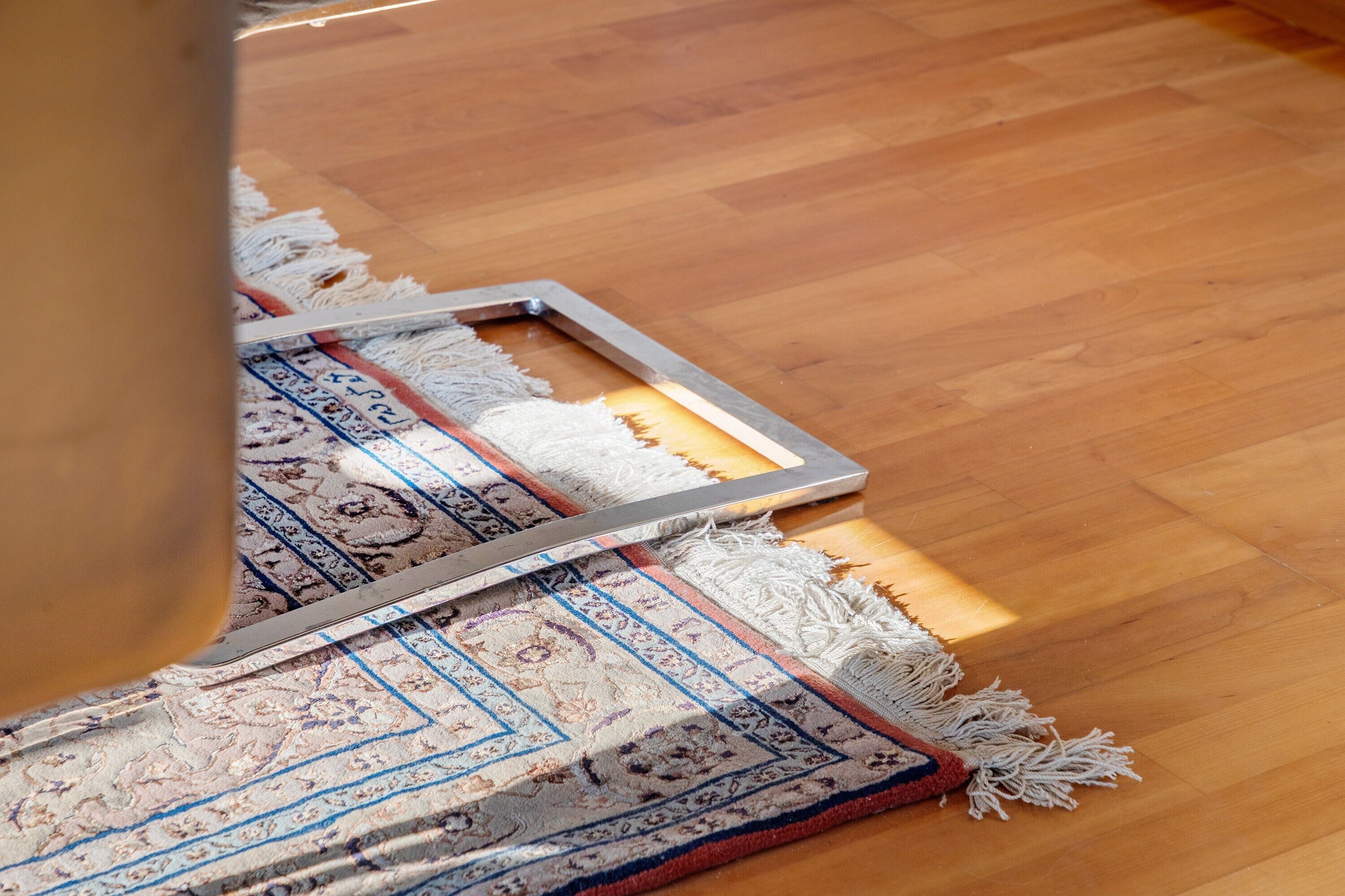 A wooden floor with a patterned rug and a metal frame.