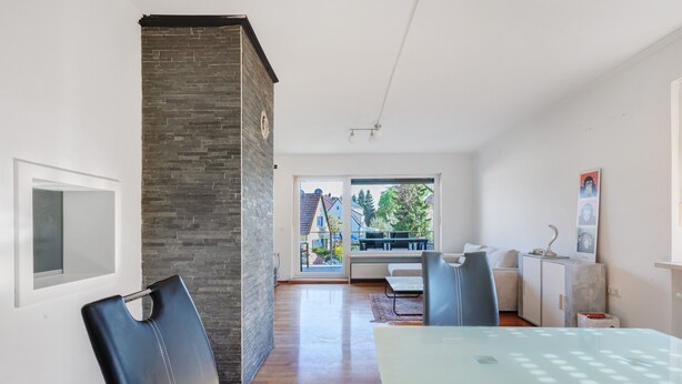 A modern living room with a glass dining table, a brick accent wall, and a view to the outside. - Apartment 'Chill in Soldnerstraße' with Balcony and Wi-Fi (Augsburg)