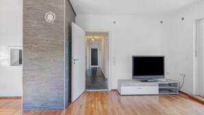 A modern living room with a flat-screen TV, wooden flooring, and a stone accent wall. - Apartment 'Chill in Soldnerstraße' with Balcony and Wi-Fi (Augsburg)