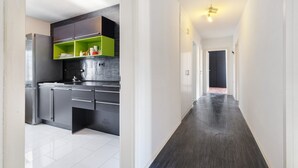 A modern kitchen with a stainless steel refrigerator, black cabinets, and a green shelf. - Apartment 'Chill in Soldnerstraße' with Balcony and Wi-Fi (Augsburg)