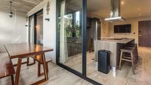 A modern kitchen with a large island, sliding glass doors, and a built-in TV. - 3 Mi to Beach! Tranquil Tulum Oasis w/ Balcony (Tulum)