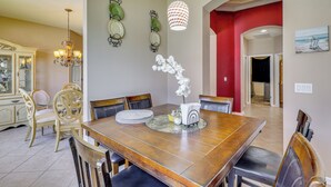 A dining area with a wooden table, chairs, a chandelier, wall decorations, and a red accent wall. - Extended Stay in Tampa Area! Spacious Home w/ Yard (Riverview)