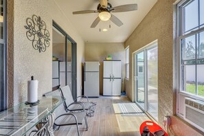 Eine Küche mit Deckenventilator, Kühlschrank und Glastisch mit Stühlen.