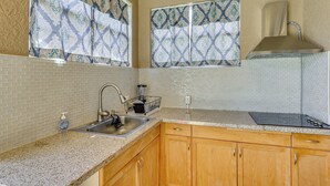 A kitchen with a sink, stove, wooden cabinets, patterned window treatments, and a clock on the wall. - Extended Stay in Tampa Area! Spacious Home w/ Yard (Riverview)