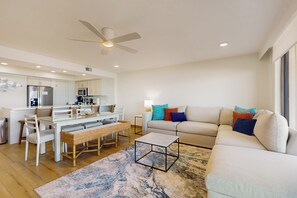 A modern living room with a sofa, a coffee table, and a dining area with a table and chairs. - Sweeping View, Luxe Perks: Suntide III - Unit 708 (South Padre Island)