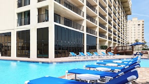 A hotel pool area with multiple levels of balconies, clear blue pool water, and sun loungers. - Sweeping View, Luxe Perks: Suntide III - Unit 708 (South Padre Island)