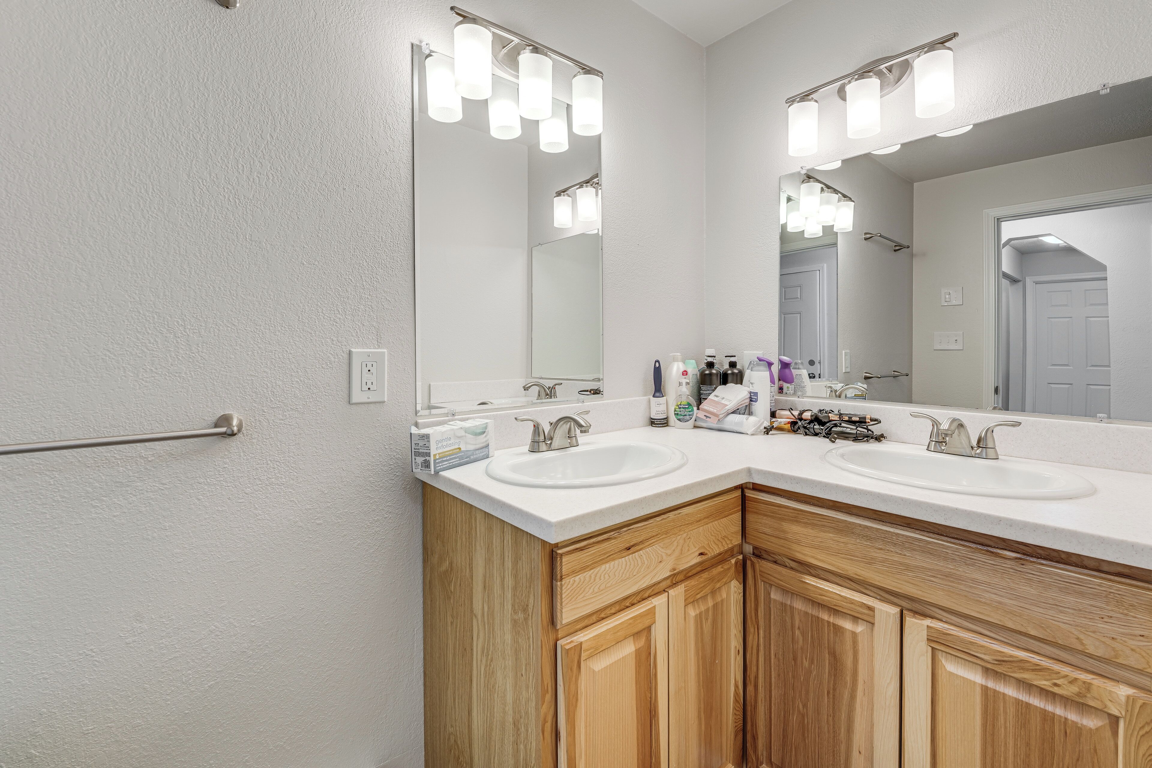 Une salle de bain avec deux lavabos, des meubles en bois, un miroir et un porte-serviettes.
