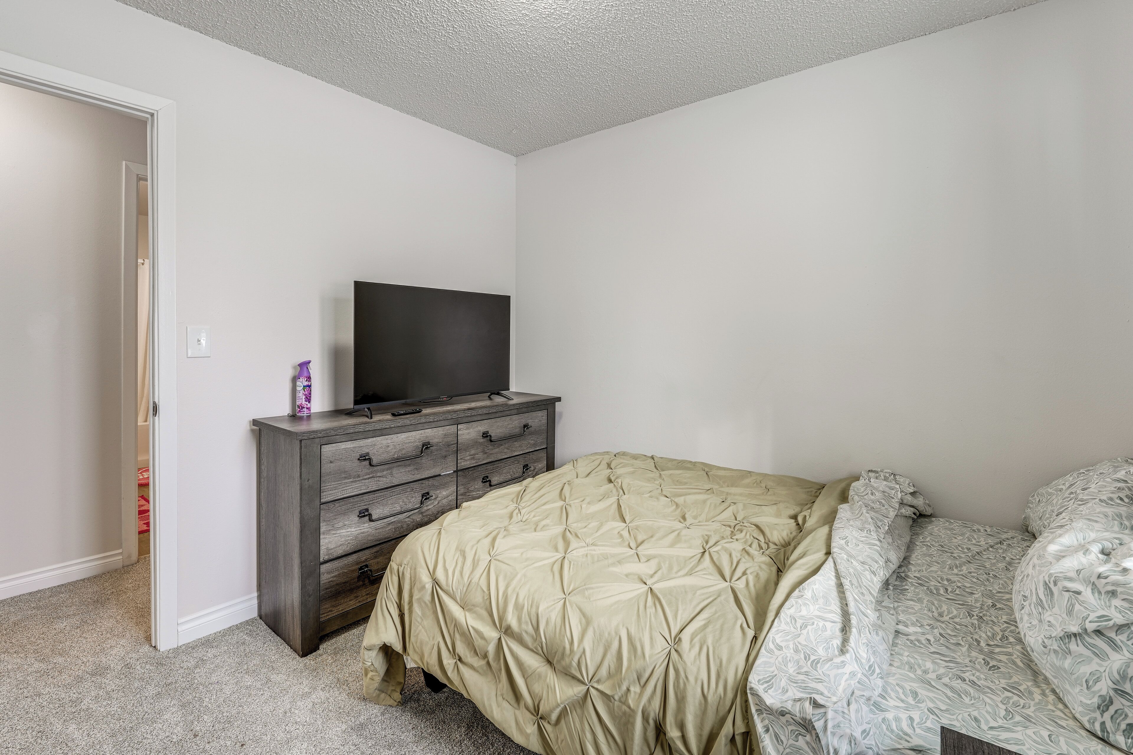 Une chambre à coucher avec un lit, une commode et un téléviseur.