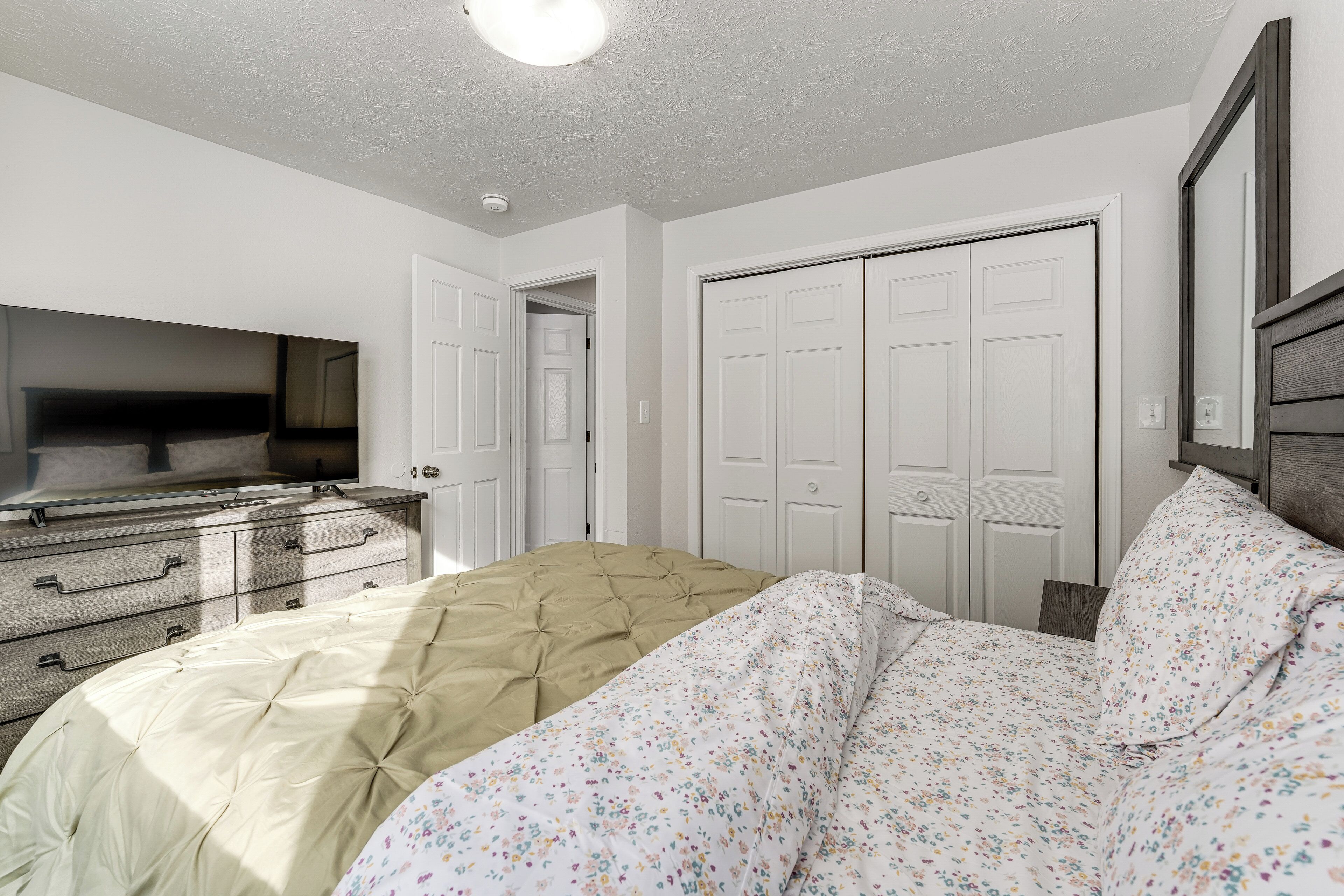 Un dormitorio con cama, cómoda, televisor y armario.