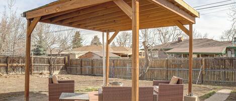 A covered outdoor patio with wicker furniture and a table.