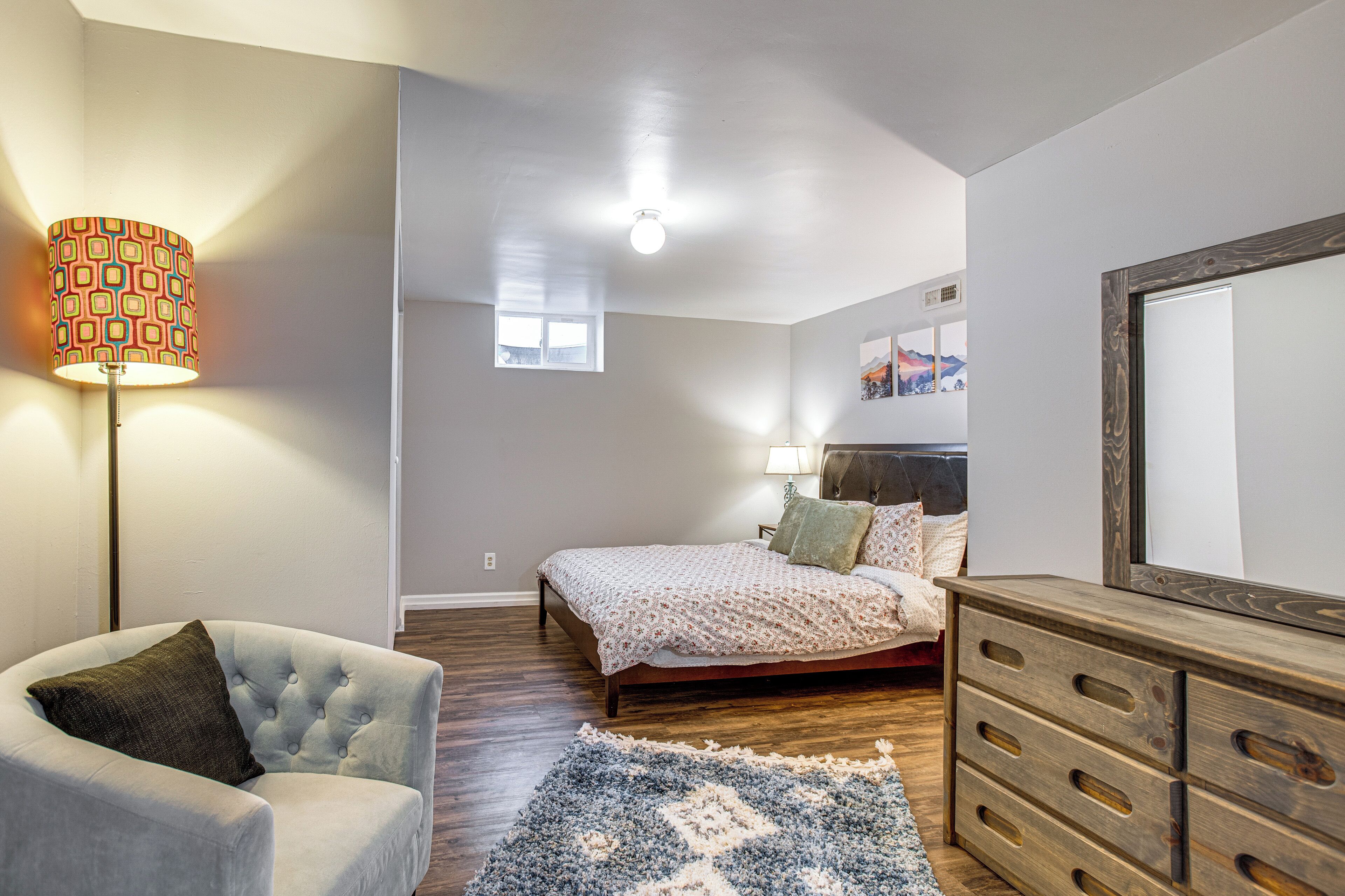 A bedroom with a bed, a chair, a dresser, a lamp, and a rug.