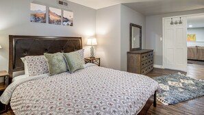 A bedroom with a large bed, a nightstand with a lamp, a dresser, and a door leading to another room. - Family Friendly! Spacious Lakewood Haven w/ Yard (Lakewood)