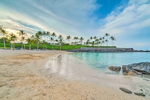 A beach with clear water, palm trees, and a rocky outcrop. - Beach Club & Pool at Big Island Resort Getaway! (Kamuela)