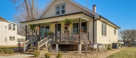 A two-story house with a porch, a staircase, and a small garden area.
