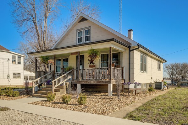 A two-story house with a porch, a staircase, and a small garden area.