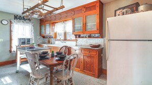 A kitchen with wooden cabinets, a refrigerator, a sink, and a dining table with chairs.