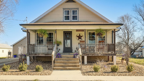 A two-story house with a front porch, a welcome sign, and a star decoration.