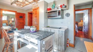 A kitchen with a granite countertop, wooden cabinets, a microwave, and a hanging light fixture.