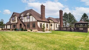 Une grande maison avec une cheminée imposante, une terrasse et un belvédère.