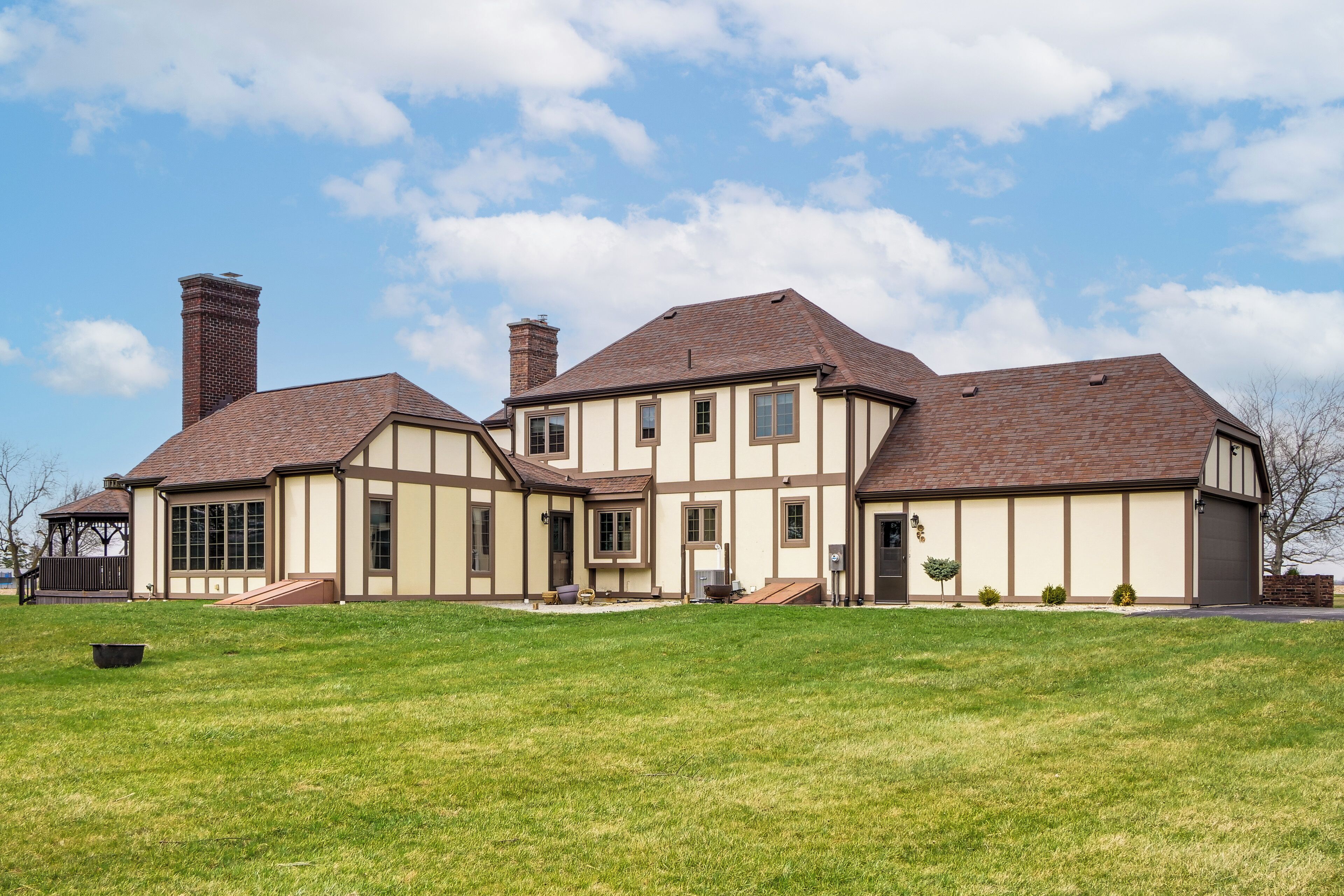 A large, two-story house with a prominent chimney, a well-maintained lawn, and a clear blue sky.