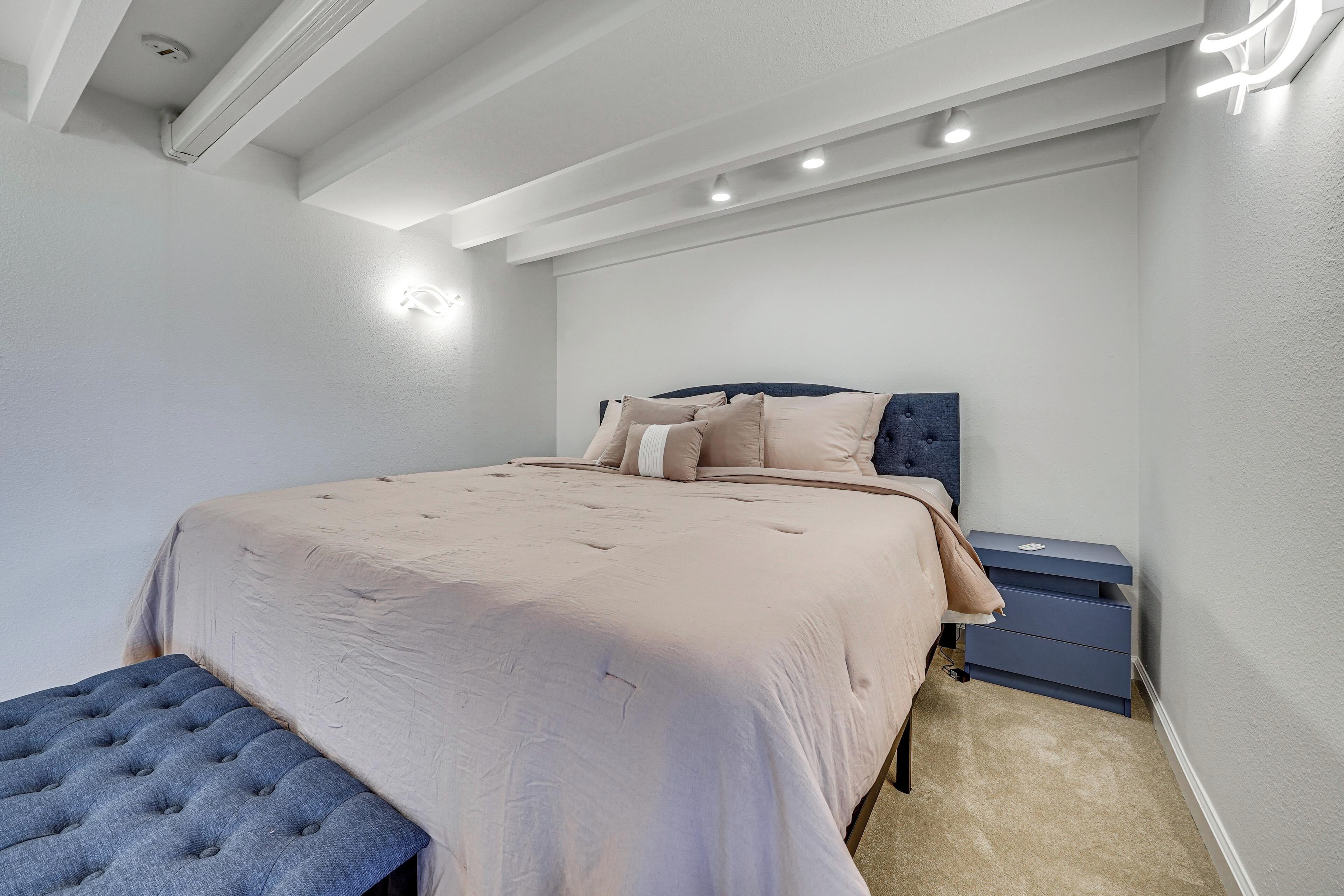 Un dormitorio con cama, mesitas de noche y un banco.