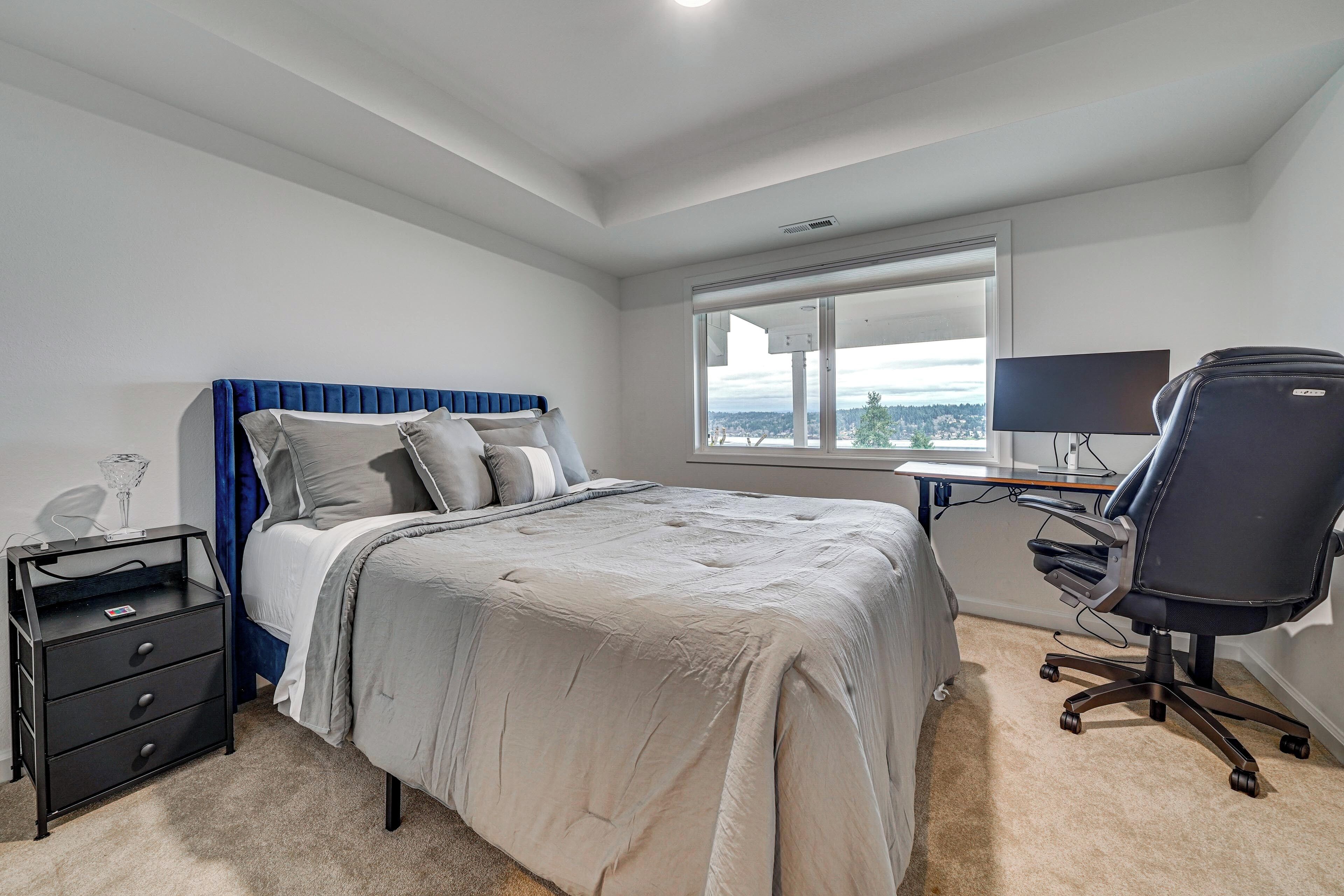 Un dormitorio con cama, escritorio, silla, mesita de noche y ventana.