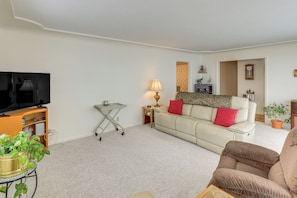 A living room with a sofa, a television, a lamp, a plant, and a small table.