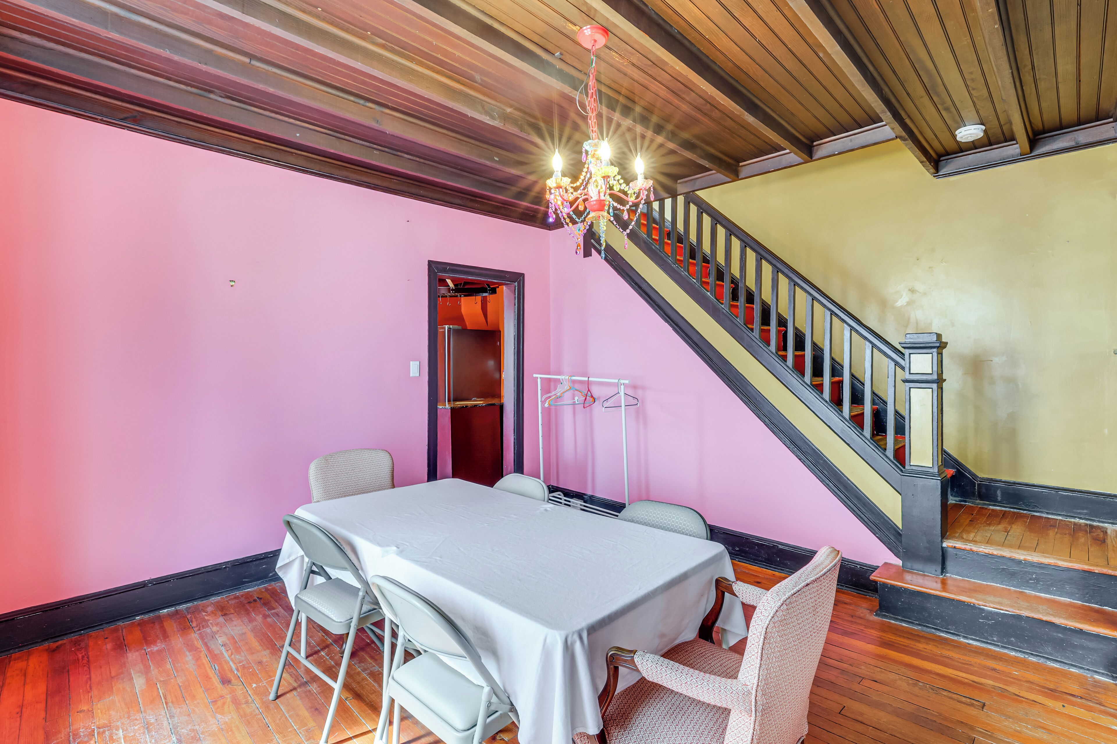 Ein Zimmer mit Tisch, Stühlen, einer Treppe und einem Chandelier.