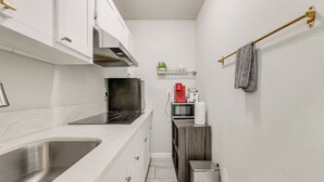 A compact kitchen with white cabinets, stainless steel sink, and a microwave. - Cozy & Convenient Condo in Compton, Pets Welcome! (Compton)