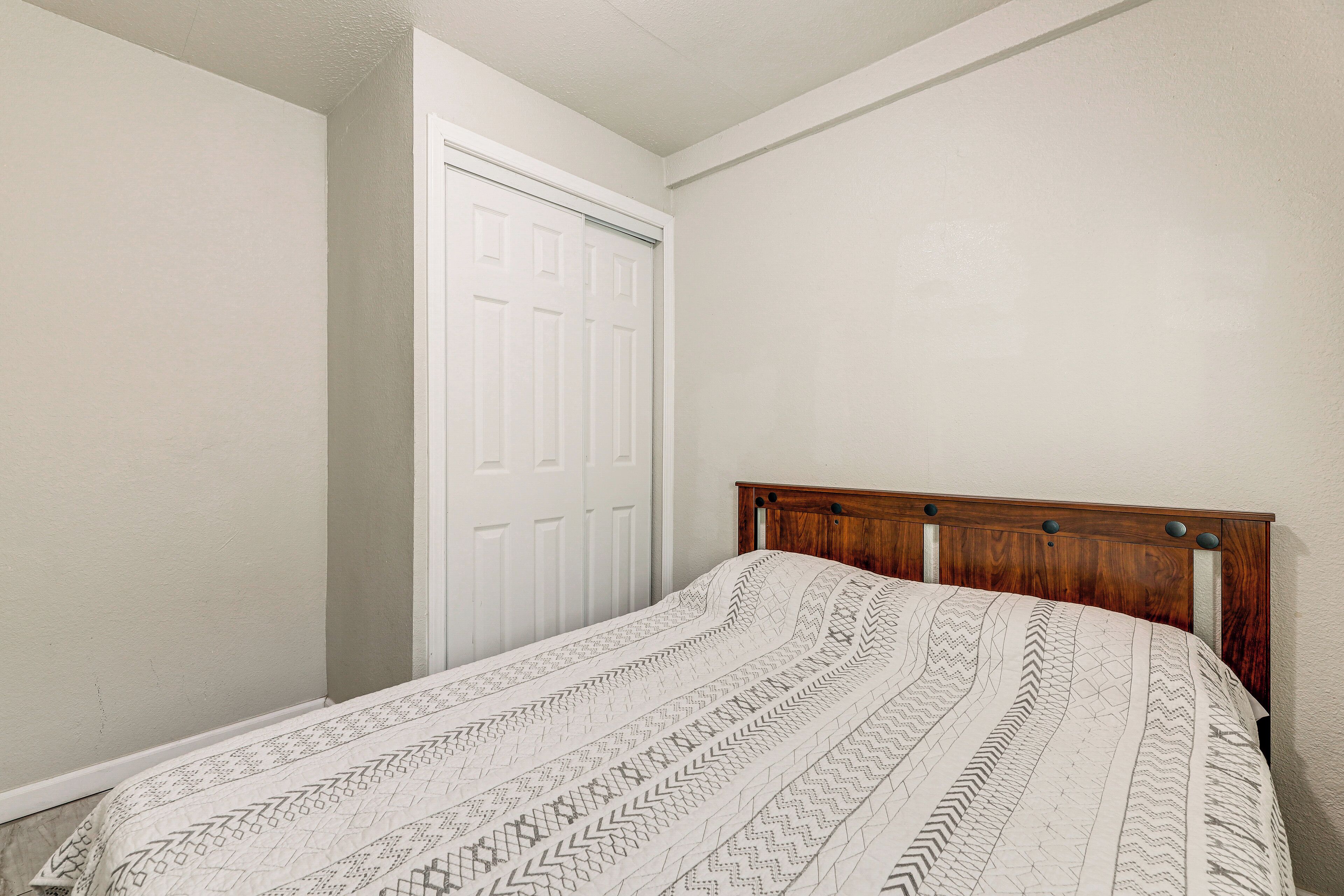 A bedroom with a wooden headboard, a patterned bedspread, and a white door.