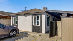 A residential building with a garage door, a parked car, and a clear sky. - Cozy & Convenient Condo in Compton, Pets Welcome! (Compton)