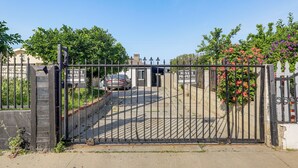 A gated entrance with a car parked inside, a clear sky, and a sign indicating private property. - Cozy & Convenient Condo in Compton, Pets Welcome! (Compton)