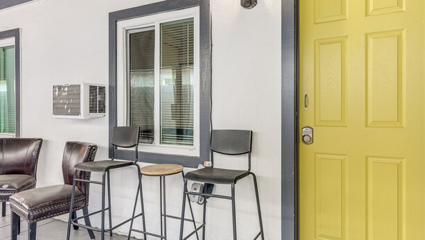 A yellow door, a window with blinds, and two chairs. - Cozy & Convenient Condo in Compton, Pets Welcome! (Compton)