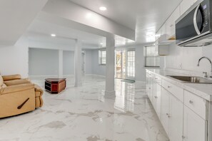 A modern kitchen with white cabinets, a stainless steel sink, and a built-in microwave. - Sunroom & Spacious Yard! Woodsy Haven in Lilburn (Lilburn)