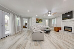 A spacious living room with a sectional sofa, a fireplace, and a ceiling fan. - Sunroom & Spacious Yard! Woodsy Haven in Lilburn (Lilburn)