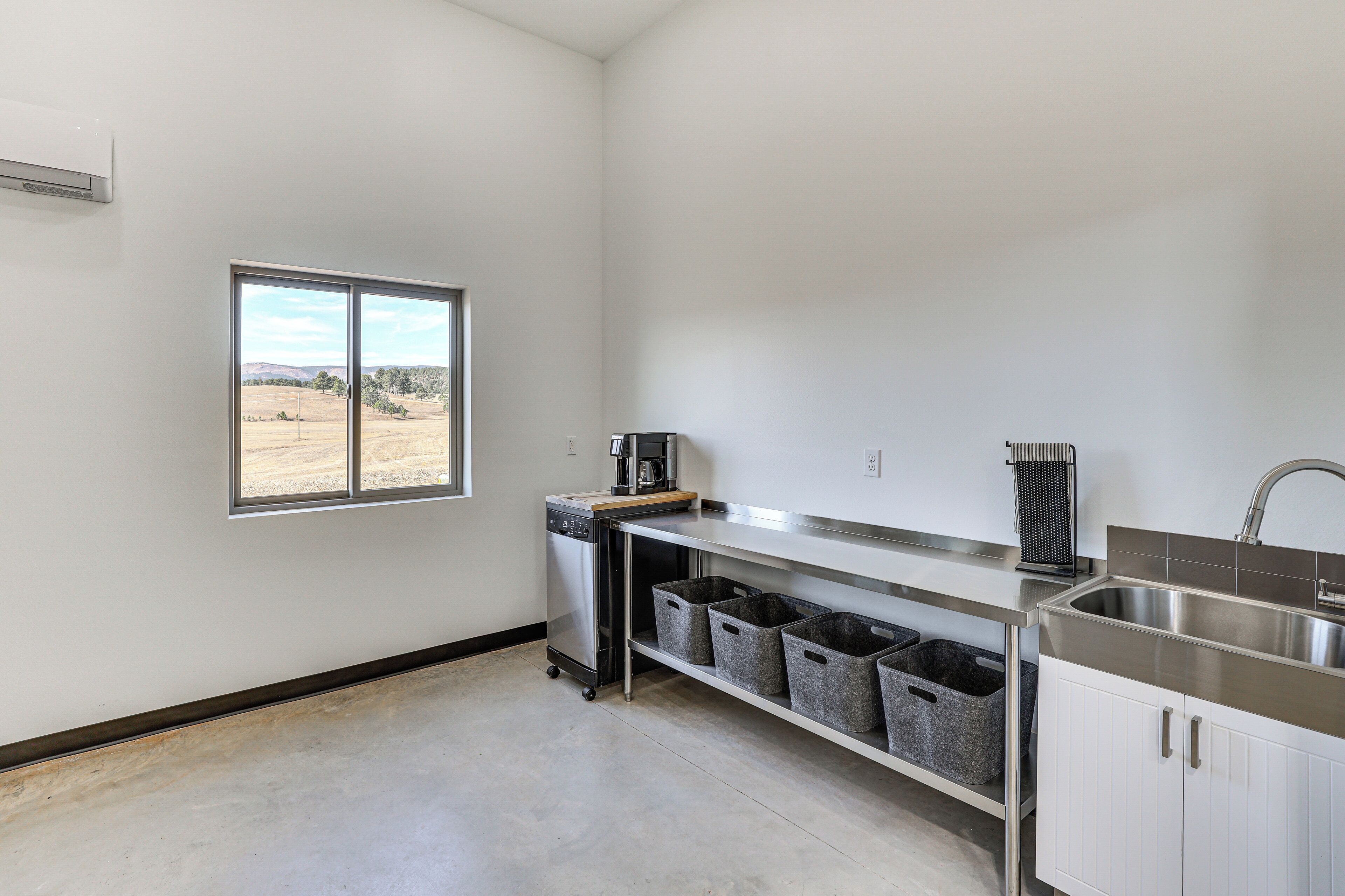 A kitchen with a dishwasher, a coffee maker, a sink, and grey storage bins.