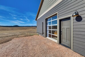 A building with a large garage door, a window, and a wall-mounted light fixture. - Trailer Parking & Hill Views! Sturgis Rally Base (Piedmont)