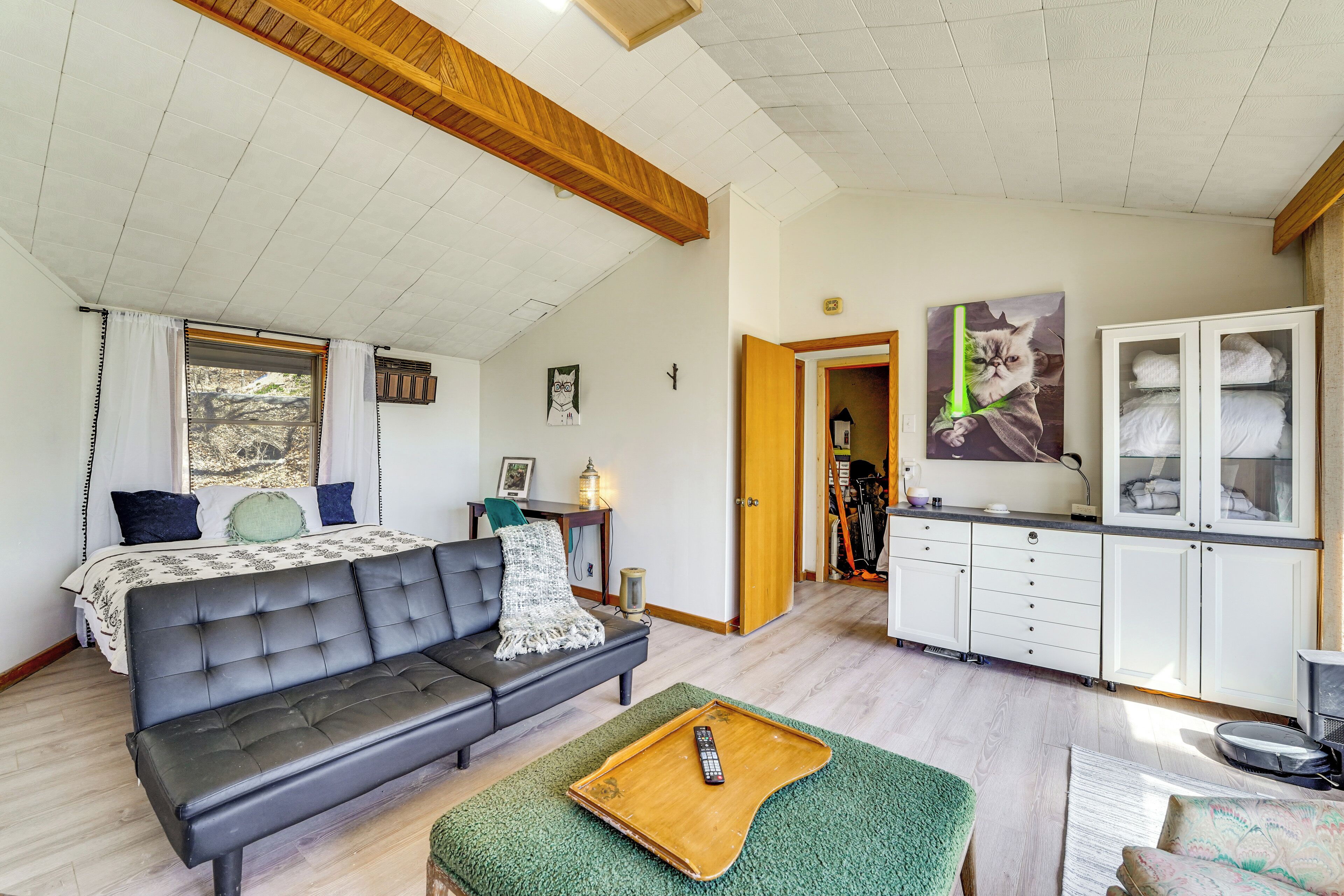 A modern living room with a sofa, a wooden coffee table, a kitchen area with cabinets, and a painting on the wall.
